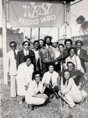 (WESL Staff ca. 1980, clockwise from top left) Larry Taylor, Frank Davis, Andre 'Spider Man' Fuller, Curtis 'Boogie Man Soul' Brown, Jim Gates, Rod 'Dr. Jockenstein' King, James 'JW' Williams, Michael Brooks, Bill 'Fox Chaser' Moore, Deborah Granger, Charles 'Sweet Charlie' Smith, Edie 'Edie B' Boatner, Sandra Gates, Peggy Meredith, Bettye Robinson